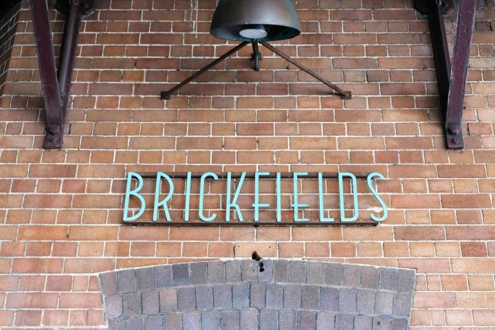 a man standing next to a brick wall